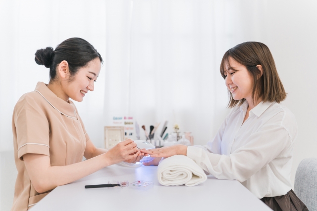ネイリストがお客様の手元をていねいに施術している様子